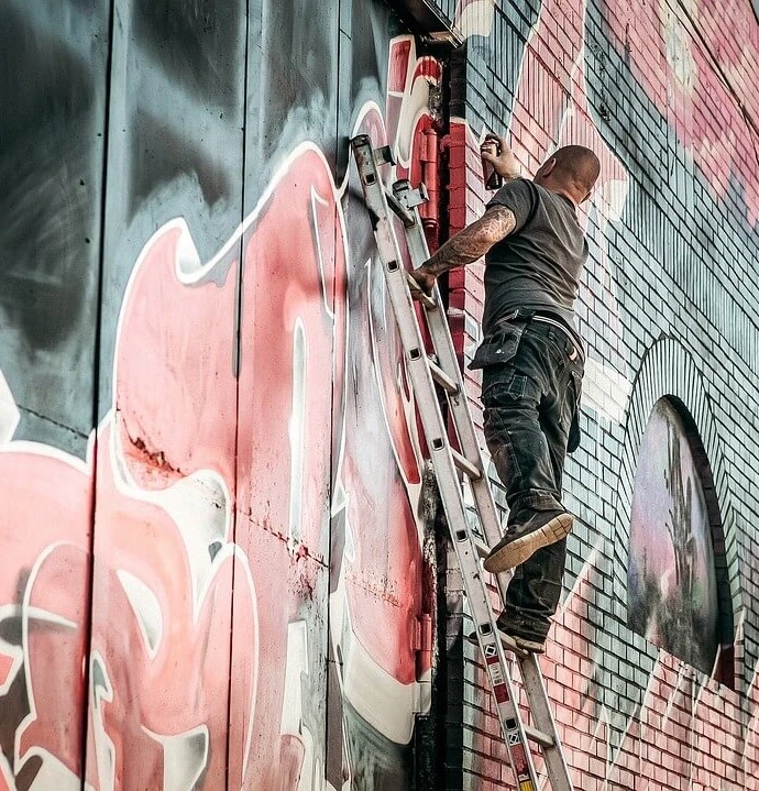 A graffiti writer creating graffiti letters on a wall